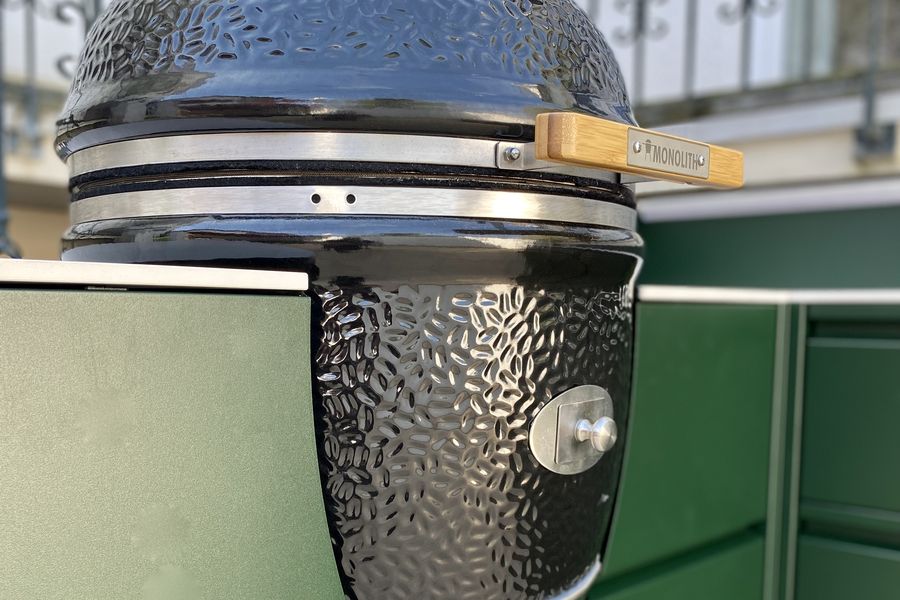 Schwarzer Keramikgrill in einer grünen Outdoor-Küche