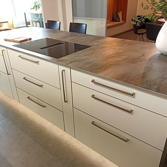 Weiße Kücheninsel mit grauer Arbeitsfläche und Induktionskochfeld mit integriertem Dunstabzug