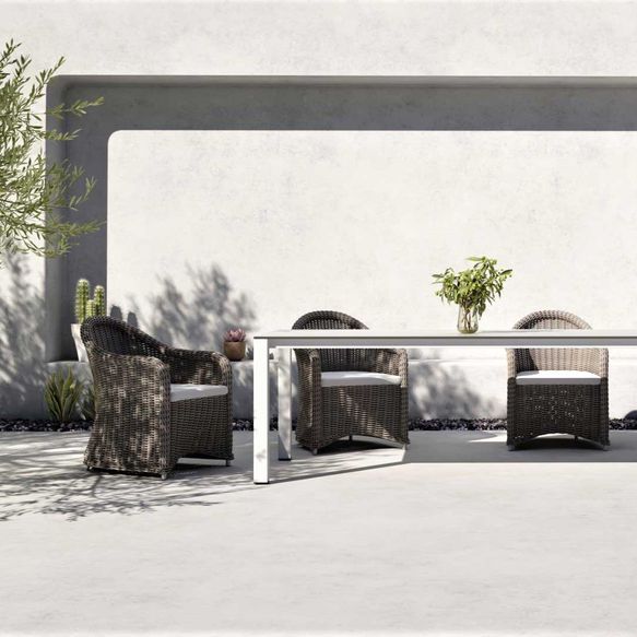 Braune Stühle aus Korbgeflecht und weißer Outdoor-Tisch