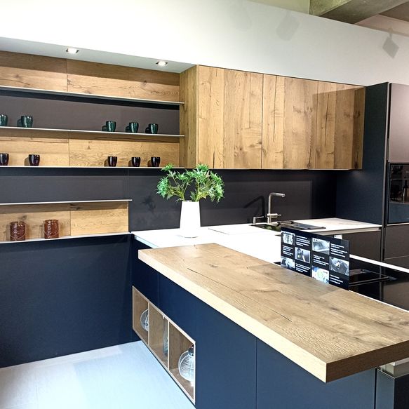 Schwarze Küche in T-Form mit Risseiche-Furnier-Fronten, weißer Keramikarbeitsplatte und angebauter Insel mit Bartop