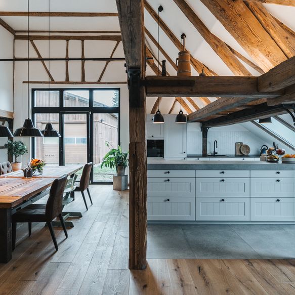 Moderne, offene, weiße Landhausküche mit Insel in rustikaler Umgebung