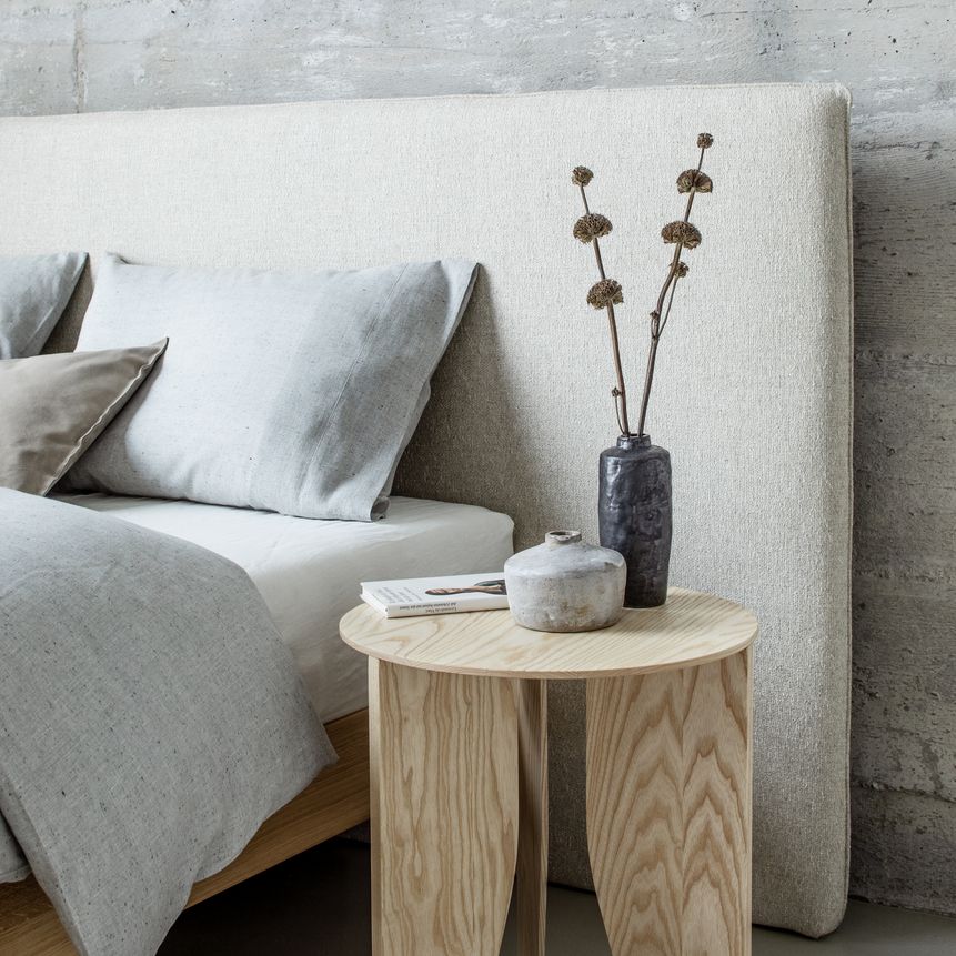 Beistelltisch aus hellem Holz und Bett