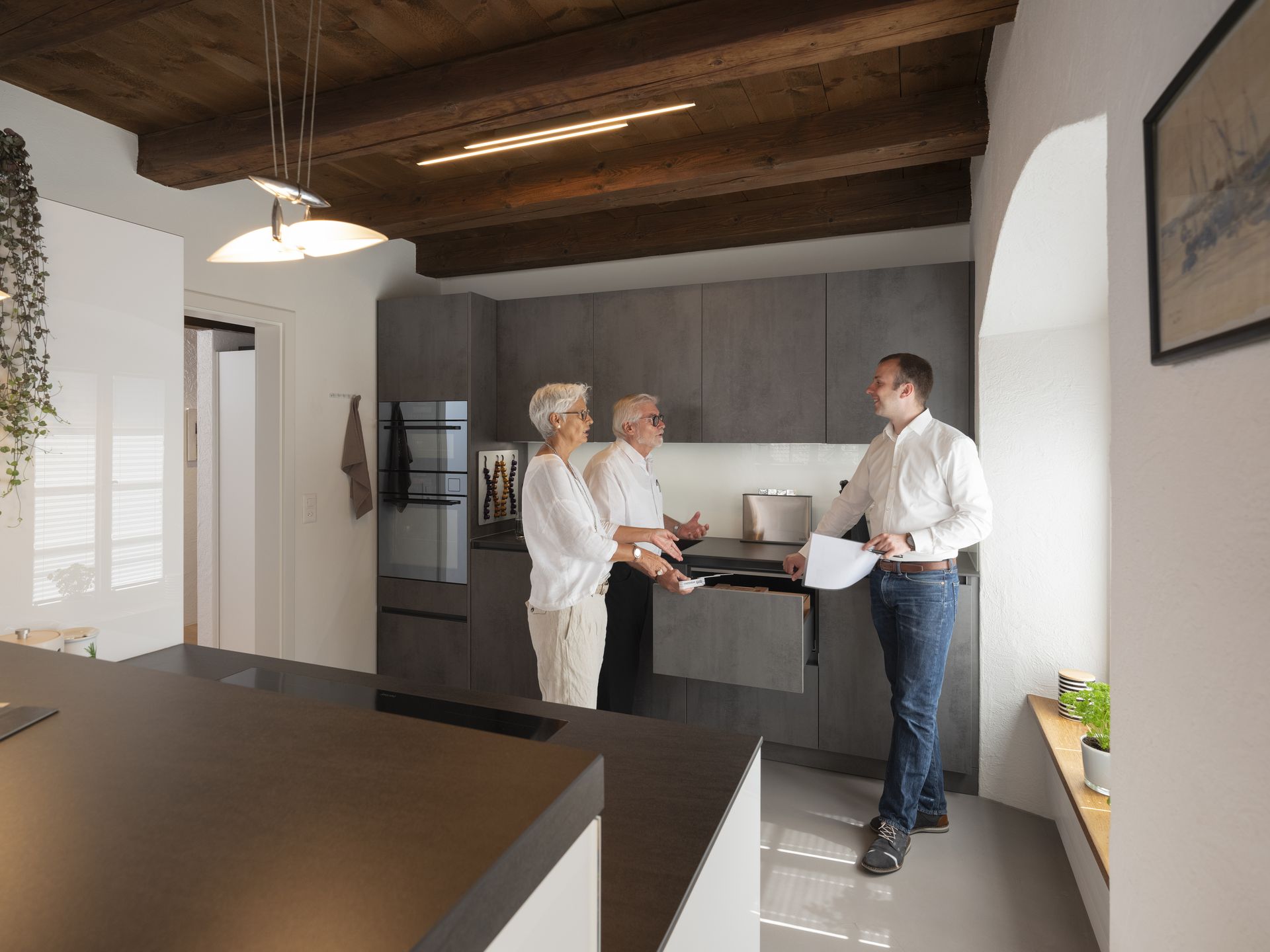 Küchenfachberater und zwei Kunden im Gespräch in Küche