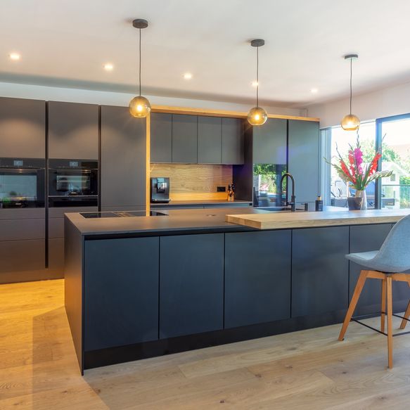 Dunkle Küche mit hellen Holzelementen und Insel