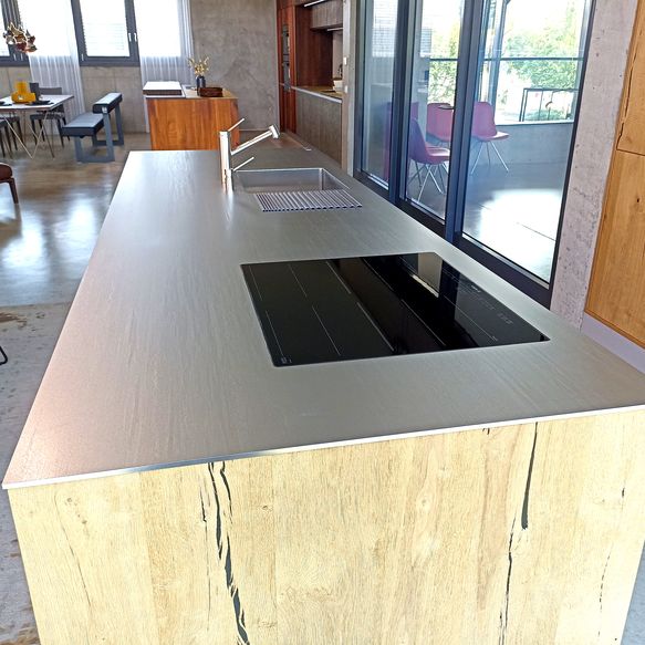 Moderne Kücheninsel mit Arbeitsplatte aus warmgewalzten und hartverchromten Edelstahl und Induktionskochfeld mit integriertem Dunstabzug
