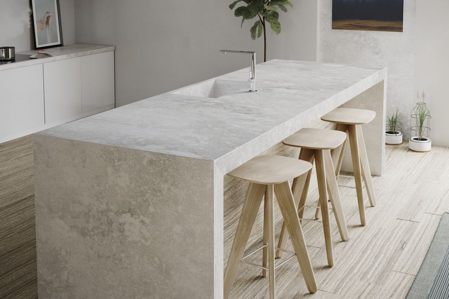 Kücheninsel in Betonoptik mit silberner Armatur und Holz-Barhockern