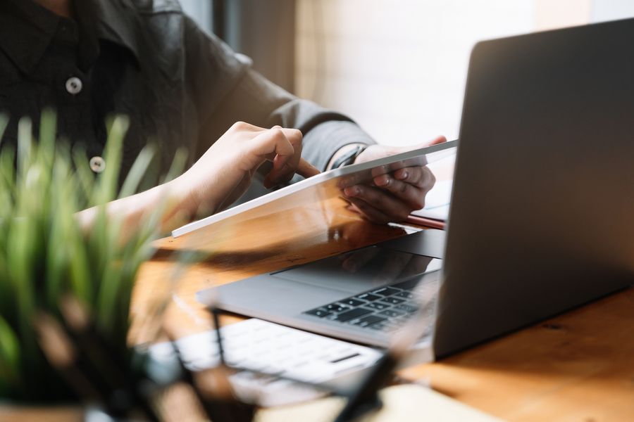 Eine Person die an einem Schreibtisch sitzt und ein Tablet bedient