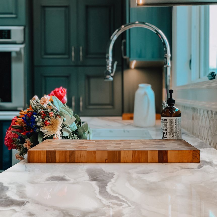 Silberne Armatur mit Marmor-Spüle und dunkelgrünen Fronten im Landhausstil