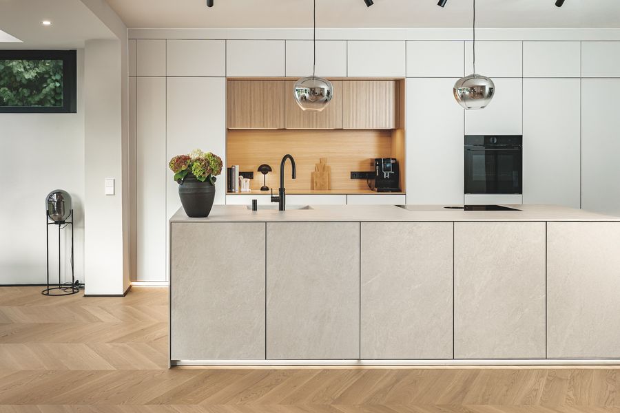 Moderne helle Küchenzeile mit Insel in Beigetönen, Nische mit Holzrückwand