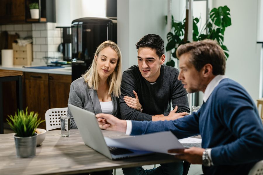 Ein Paar und ein Verkaufsberater am Tisch in einem Beratungsgespräch