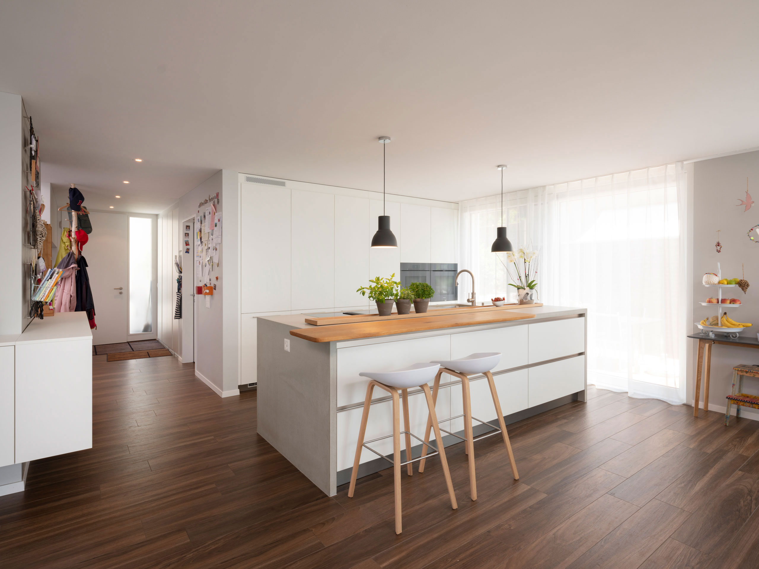 Weiße Wohnküche mit Hochschrankwand, langer Insel und TV-Schrank mit Ablagefläche
