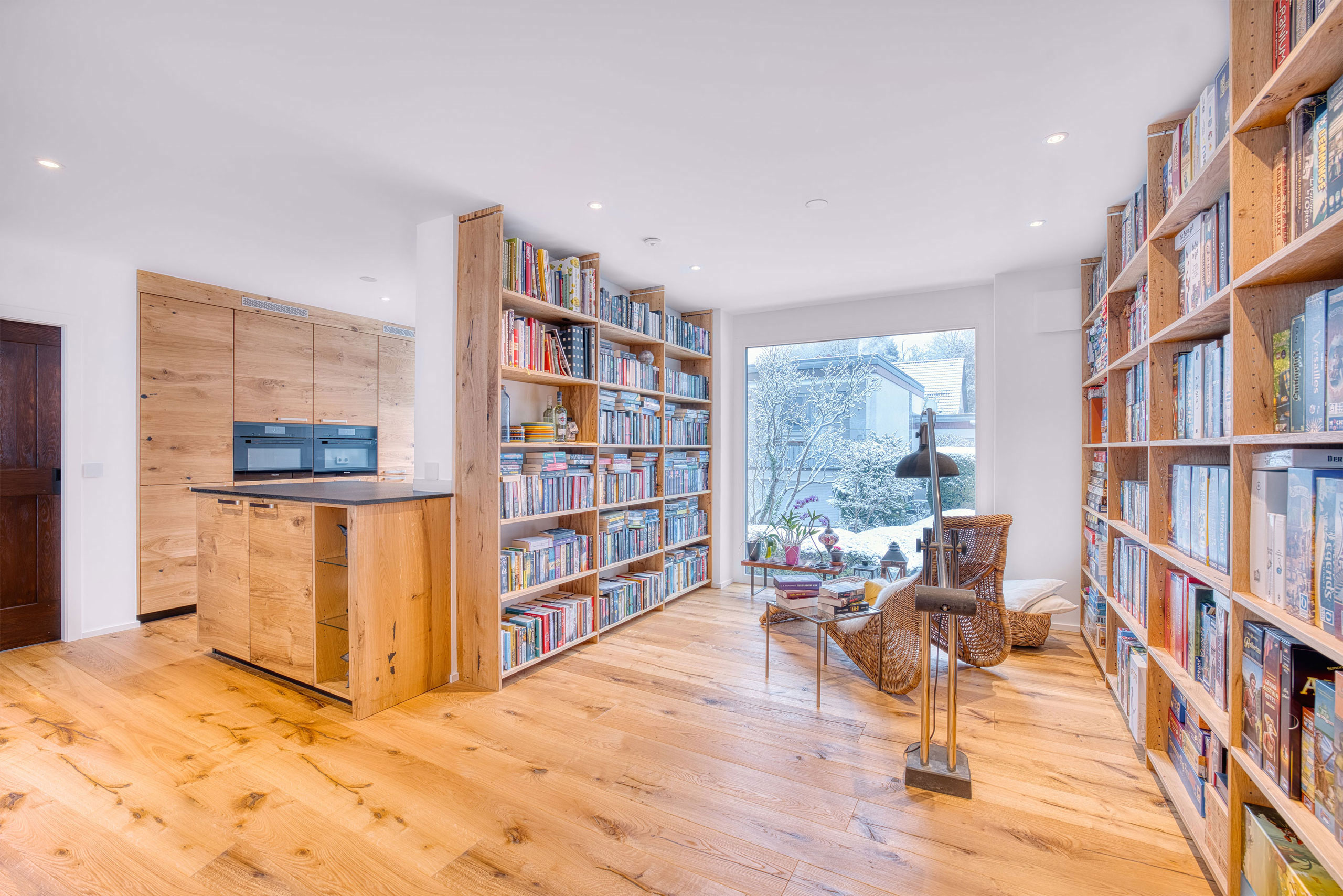Helle Massivholzküche mit dunkler Arbeitsplatte aus Naturstein mit passendem Bücherregal