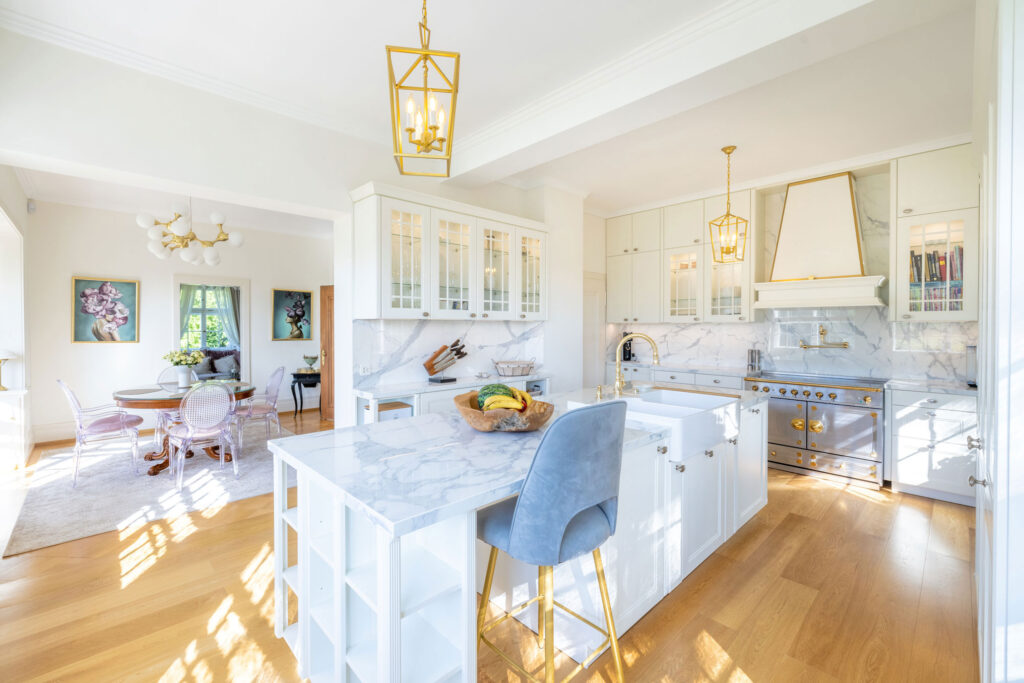 Weiße, elegante Landhausküche mit goldenen Elementen