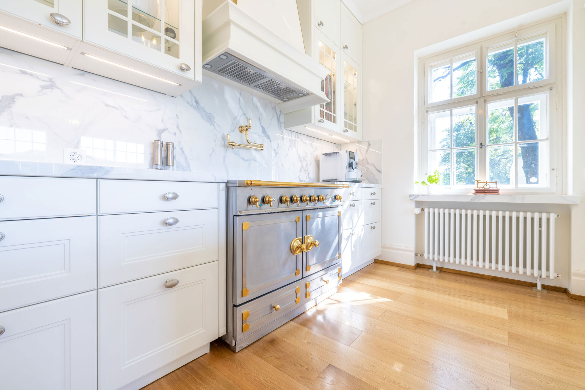 Weiße, elegante Landhausküche mit goldenen Elementen