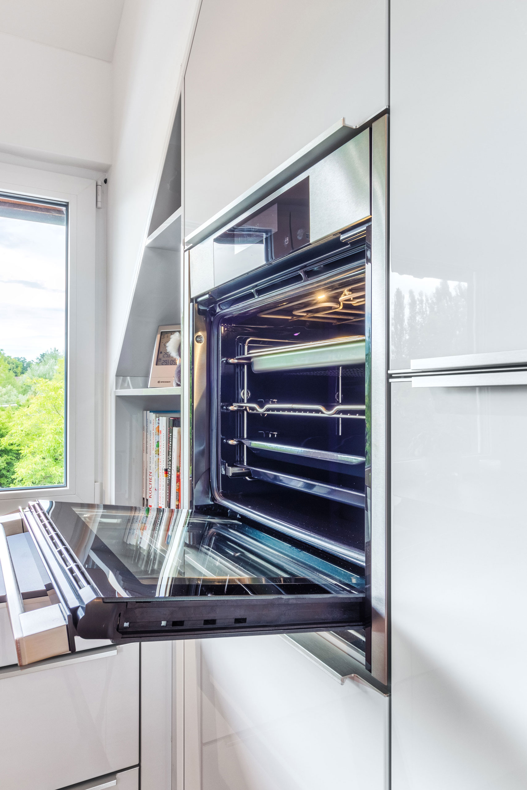 Weiße Hochglanz Küche mit offenem Backofen und roter Insel im Zentrum