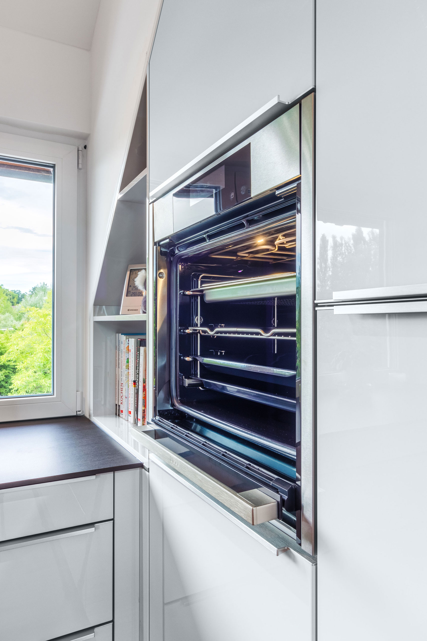 Weiße Hochglanz Küche mit offenem Backofen und roter Insel im Zentrum