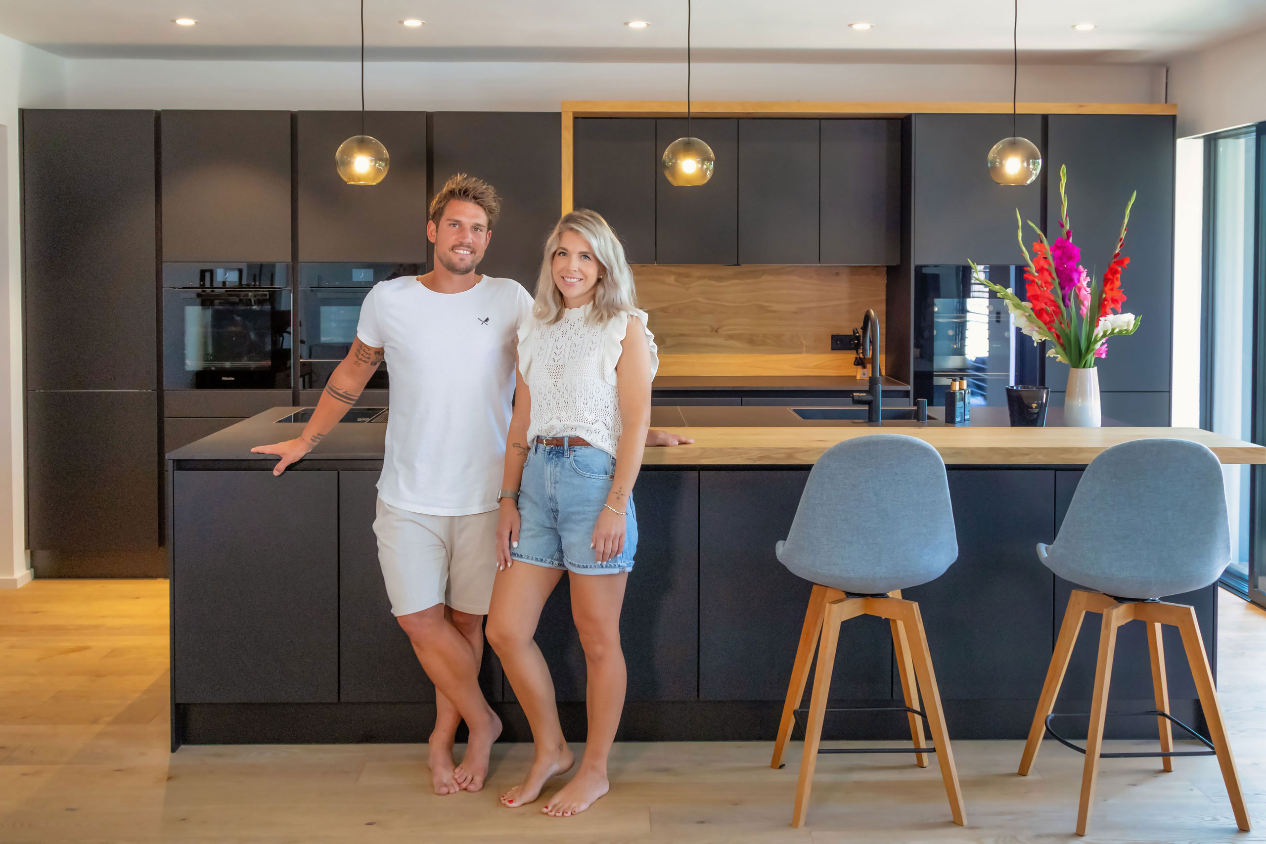 Dunkle Küche mir Holzelementen und Bartop an Insel mit Kunden