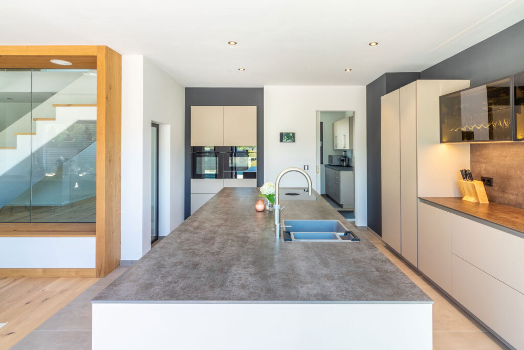 Küche in beige mit Kochinsel und langer Zeile mit Glas-Elementen
