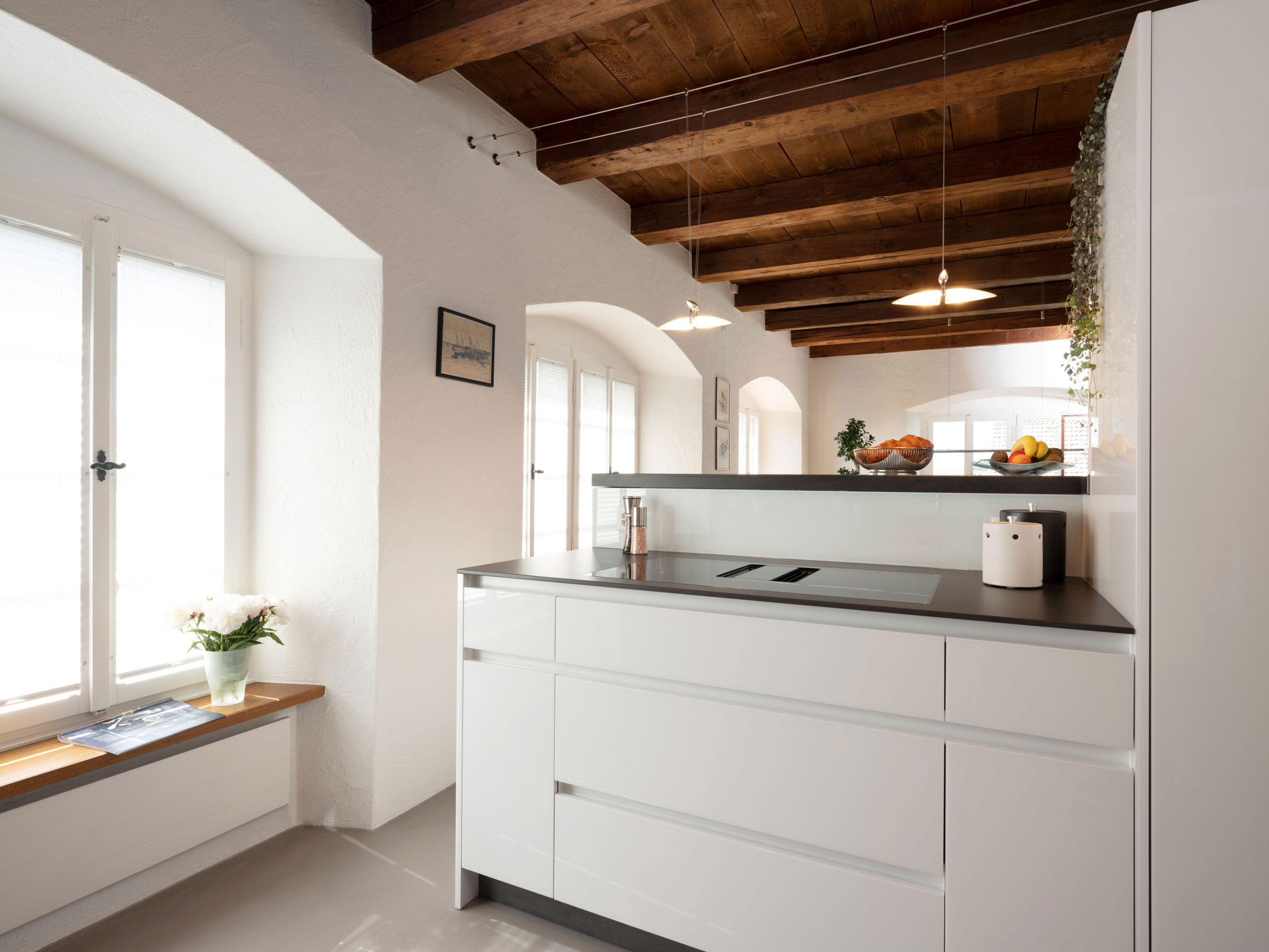 Weiße Küche in Altbau-Wohnung mit erhöhter Theke aus Naturstein