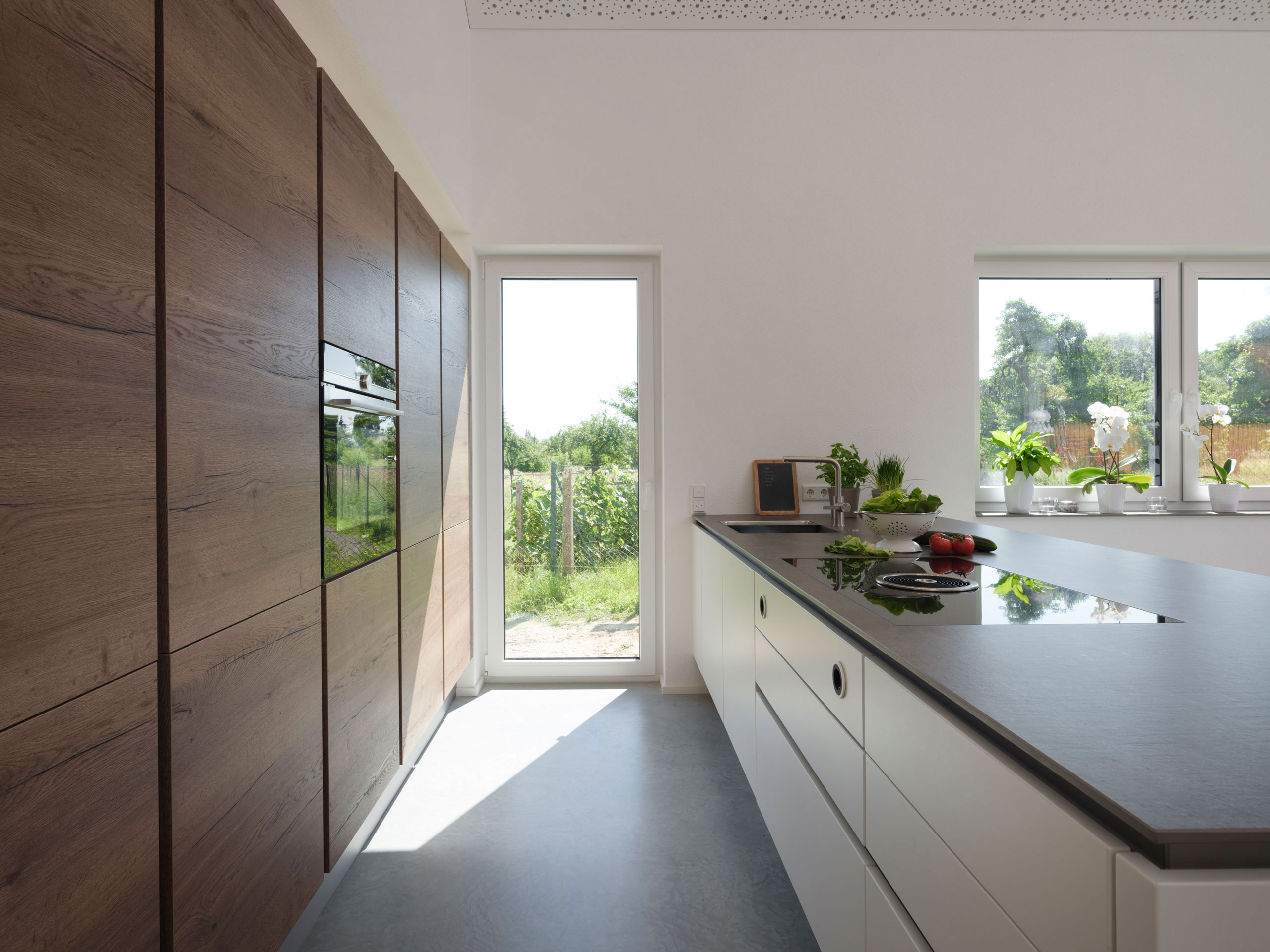 Weiß-grauer Kochinselblock mit Holz-Hochschrankwand