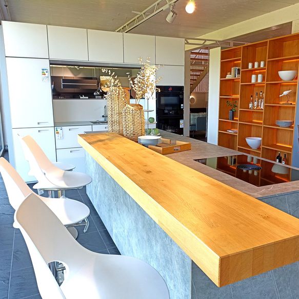 Weiße Küchenzeile mit vielen Schränken und großer Insel mit Bartop und großes Holzregal